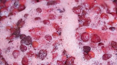 Çilekler tencerede kaynayıp lezzetli ev yapımı reçel yapıyorlar. Tam kare yakın çekim.