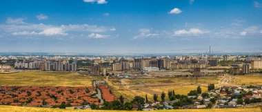 Kırgızistan 'ın kalbinde geniş ve gelişmekte olan bir atmosfer yaratan, yerleşim evleri ve inşaat alanlarının yer aldığı kentsel Bişkek manzarasının panoramik görüntüsü.