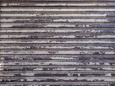 Yıpranmış metal rulo kapılar, gerçek yaşam dokusu ve arkaplan parçalı boya sergiliyor..