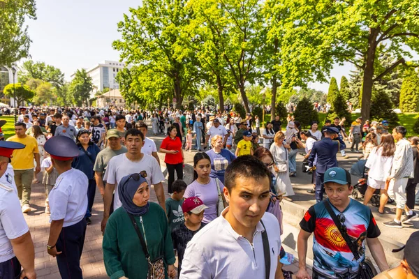 Yüzlerce insan, karışık cinsiyetler ve yaşlar, canlı bir halk parkında yürüyor. İlgi ve kararlılığın çeşitli ifadeleri, 8 Mayıs 2025 'te Kırgızistan' ın Bişkek kentindeki olgun ağaçların altında sahneyi doldurdu.