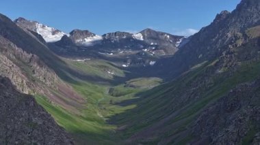 Huzurlu bir vadide, akan bir nehirle görkemli bir dağ sırası yükseliyor. Yamaçlarda akan bulutların gölgeleri. Drone hiper hızı.