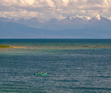 Issyk-Kul Gölü 'nün sakin sularında, ufukta karla kaplı dağlar olan iki sakin adam.