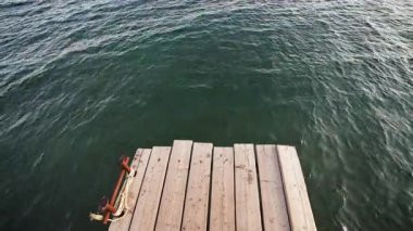 Serene ahşap iskele, sakin suda dinlenen çapa ve ip içerir. Limana yakın huzurlu bir açık hava, sakin bir atmosfer yaratıyor..