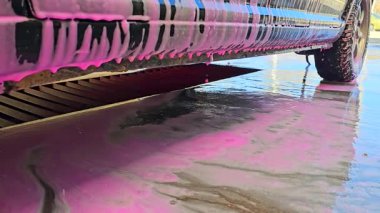 Araba köpük ve suyla iyice yıkanır. Parlak güneş ışığı manzarayı güzelleştirir. Açık havada temizlik ve canlılık..