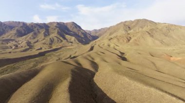 Kırgızistan 'daki uçsuz bucaksız, sakin dağları görüntüler. Kuru bitki örtüsü ve berrak gökyüzü doğal ve görkemli bir atmosfer yaratır. Dolly ileri kamera hareketi.
