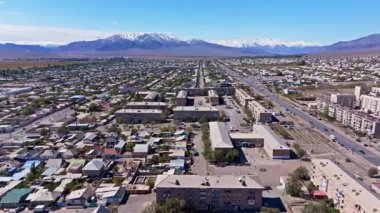 Yörüngedeki hava manzarası, yerleşim yerleri ve caddelerle yayılan şehir manzarasını yakalıyor. Karla kaplı dağlar güneşli gökyüzünün altında sakin ve geniş bir zemin oluşturur..