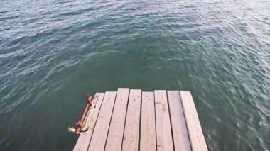 Serene ahşap iskelesi, sağlam bir ip ve metal krampon içeren sakin suyun yanında yer alır. Huzurlu dış mekan rahatlama ve tefekküre davet eder..