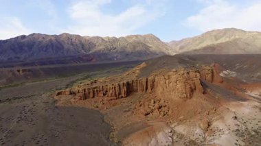 Hava görüntüsü Kırgızistan 'daki dağların ve aşınmış kanyonların çarpıcı jeolojik oluşumlarını yakalar. Parlak gündüz ışığı bu kurak manzaranın doğal güzelliğini arttırır..