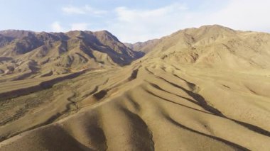 Kırgızistan 'daki uçsuz bucaksız, sakin dağları görüntüler. Parlak gündüz gökyüzü altında pürüzsüz aşınmış tepeler.