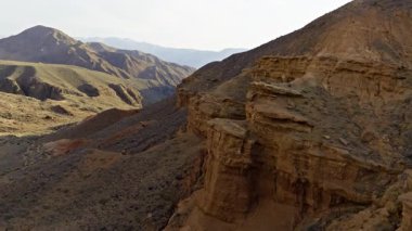 Kırgızistan 'da sonbahar akşamı aşınmış kumtaşı ile çöl kanyonunun insansız hava aracı görüntüsü. Dolly ileri kamera hareketi.
