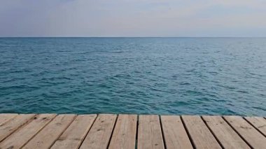 Ahşap iskele sakin okyanus ufkuna doğru uzanıyor. Sakin atmosfer huzur ve huzuru çağrıştırıyor, rahatlama veya meditasyon için mükemmel..