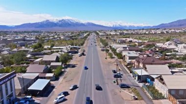 Arabalar, Balykchy, Kırgızistan 'daki yerleşim yerleriyle çevrili küçük bir kasabada düz bir yolda ilerliyor - 2 Ekim 2025