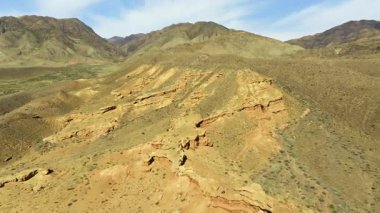 Uçsuz bucaksız kayalık arazide aşınmış kumtaşı duvar oluşumları ve seyrek bitki örtüsü bulunur. Drone görünümü.