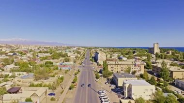 Hava manzarası, binalar, arabalar, ağaçlar ve büyük bir su kütlesiyle çarpıcı Balykchy şehir manzarasını yakalar. Uzaktaki geniş dağlar dingin havayı arttırır..