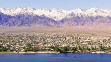 Balykchy şehrinin yakınındaki görkemli dağ sıralarını görüntüler. Yelkenliler sakin Issyk-Kul Gölü 'nde gündüz vakti gökyüzünün altında süzülerek muhteşem bir manzara yaratırlar..