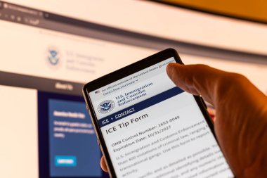 neighbor holding a phone with US ICE website sending tip in Balykchy, Kyrgyzstan - February 13, 2026