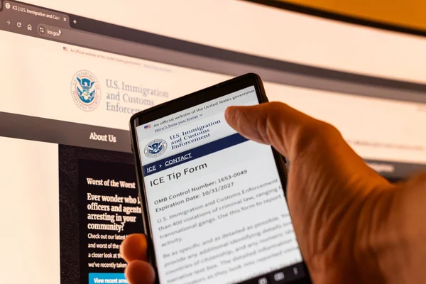 Beyaz el, Balykchy, Kırgızistan 'da ABD Göçmen Bürosu' nun internet sitesinden bir telefon tutuyor. 13 Şubat 2026