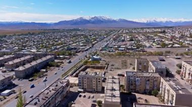 Kırgızistan 'daki geniş şehir manzarasını görüntüler. Berrak gökyüzü huzurlu atmosferi yükseltiyor, şehir yaşamını dağ zeminine karşı sergiliyor.