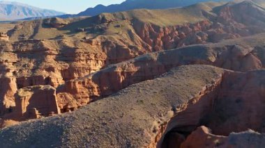 Kırgızistan 'ın kurak arazisine aşınmış kırmızı kumtaşı oluşumları ve engebeli kanyonlar hükmediyor..