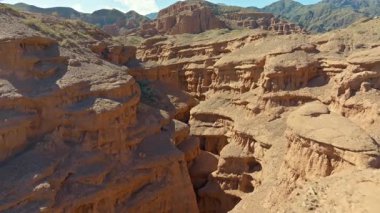 Kırgızistan 'daki görkemli kanyon manzaraları katmanlı tortul kaya oluşumlarını gösteriyor. Uçurumlar arasındaki dar zigzag yarığının insansız hava aracı görünümü.