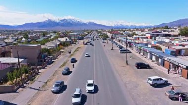 Balykchy, Kırgızistan 'da güneşli bir cadde boyunca yürüyen ve alışveriş yapan altı yetişkin grubu - 2 Ekim 2025