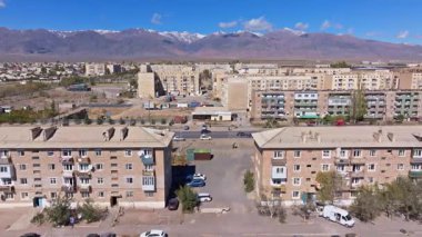 Şehir merkezi, birden fazla apartman ve kazıcı ve vinçle bir inşaat alanı yakalıyor. Berrak gökyüzünün altındaki dağlarla çevrelenmiş sakin atmosfer.