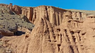 Kırgızistan 'da berrak mavi gökyüzünün altında görkemli aşınmış kumtaşı kayalıkları yükseliyor. Küçük bir kuş, bu sakin, eski topraklarda bir kaya sütunun tepesine tünedi..