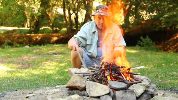 Homme assis près du feu de camp — Video