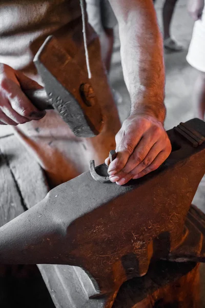 The blacksmith forging glowing horseshoe — Stock Photo, Image