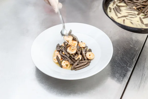 Räkor serveras med svart pasta Stockbild