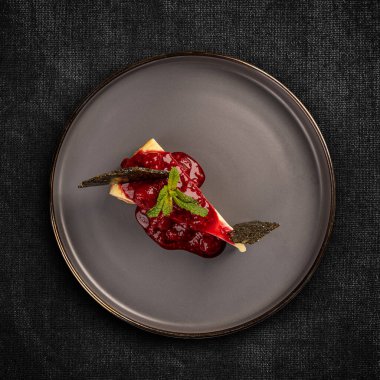 Koyu arkaplanda ahududu reçelli düz peynirli kek.