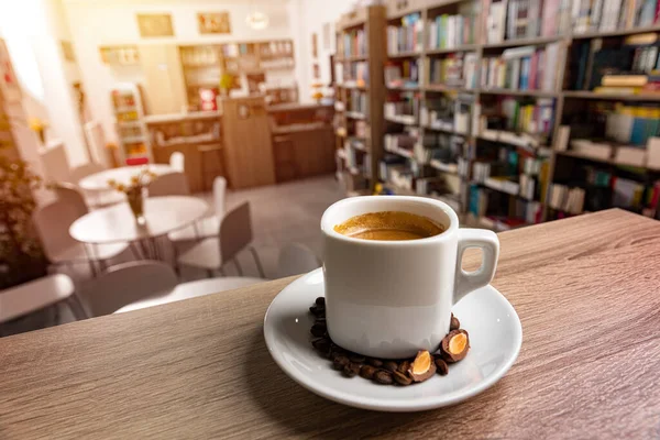 Λευκό Φλιτζάνι Καφέ Ένα Πιατάκι Στο Τραπέζι Θολό Φόντο Βιβλιοπωλείο Εικόνα Αρχείου