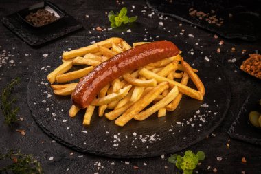 Kızarmış domuz sosisi, patates kızartmasıyla servis edilir.