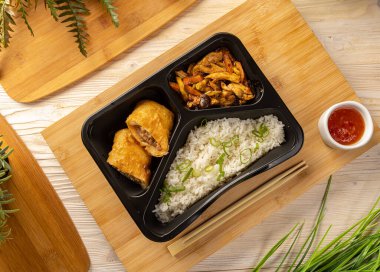 Domuz etli pilav ve bambu dilimleme tahtasının üzerinde acı biber sosuyla servis edilen tavuk güveci.