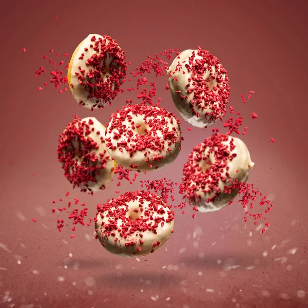 Létající Koblihy Glazované Bílou Čokoládou Zdobené Lyofilizovanými Jahodami Červeném Pozadí — Stock fotografie