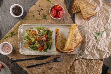 Lezzetli ızgara peynirli sandviç ve restoran masasında servis edilen taze salata.
