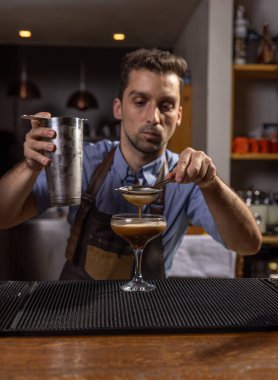 Barmen, karışımı bardağa dikkatlice dolduruyor.