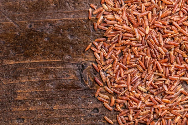 Arroz vermelho no fundo de madeira — Fotografia de Stock