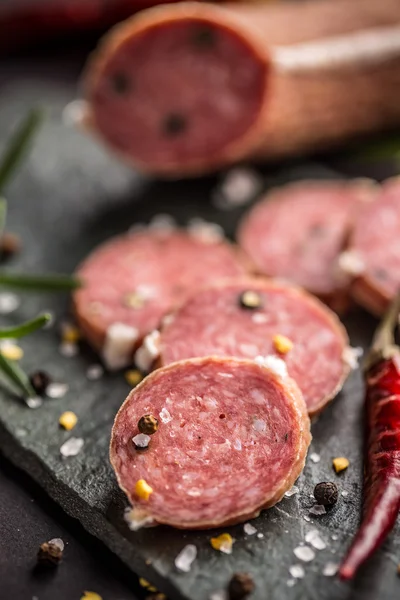 Salami med peppar på svart — Stockfoto