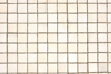 Background from a wall made of square beige mosaic tiles