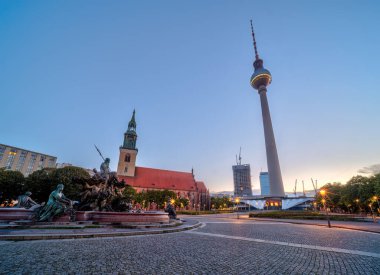 Berlin 'deki Alexanderplatz' da ünlü TV kulesi ve şafakta St. Marys kilisesi.