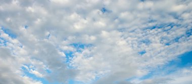 Pofuduk beyaz kümülüs bulutları parlak mavi gökyüzüne karşı.