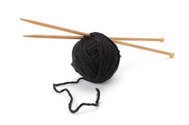 Siyah bir iplik yumağı düz bir yüzeyde, içine iki tahta örgü iğnesi sokulmuş. Gevşek bir ip dışa doğru uzanıyor, kopyalama alanı ile basit ve odaklanmış bir zanaat sahnesi yaratıyor.