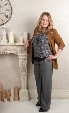 Bir kadın bir süet ceket ve pantolon şöminenin yanında ayakta