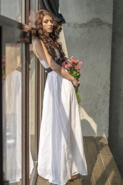 Bir gelinlik ve makyaj ile şenlikli bir buket gül ile saçlı kız