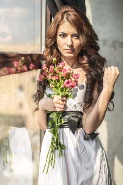 Bir gelinlik ve makyaj ile şenlikli bir buket gül ile saçlı kız