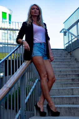 İnce, atletik, uzun, sarışın kız ceketi bankta.