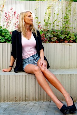 İnce, atletik, uzun, sarışın kız ceketi bankta.