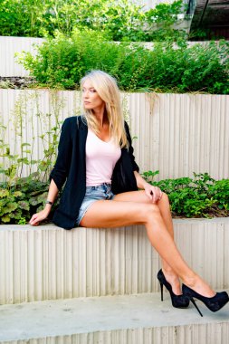 İnce, atletik, uzun, sarışın kız ceketi bankta.