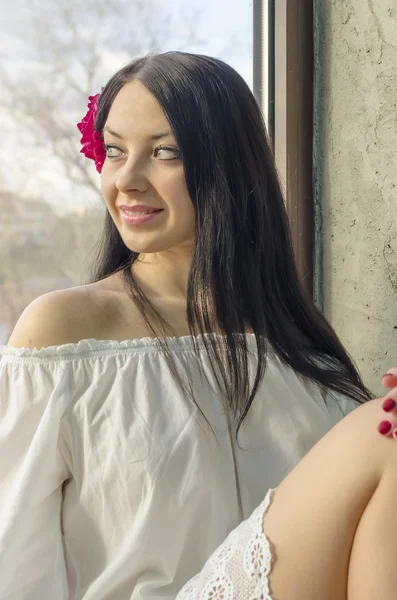 Girl with long hair in a linen shirt in the window — Stock Photo, Image